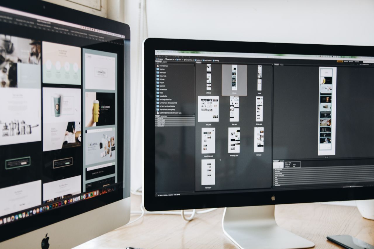 A contemporary office setting showcasing two computer screens with web design layouts, highlighting tech use and efficiency.
